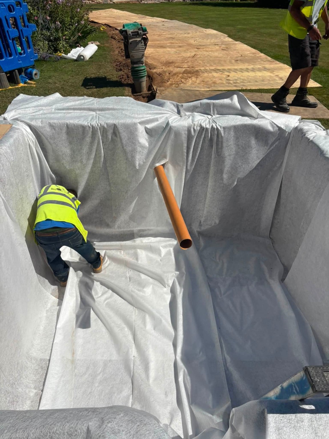 Lined excavation and drainage pipe being installed