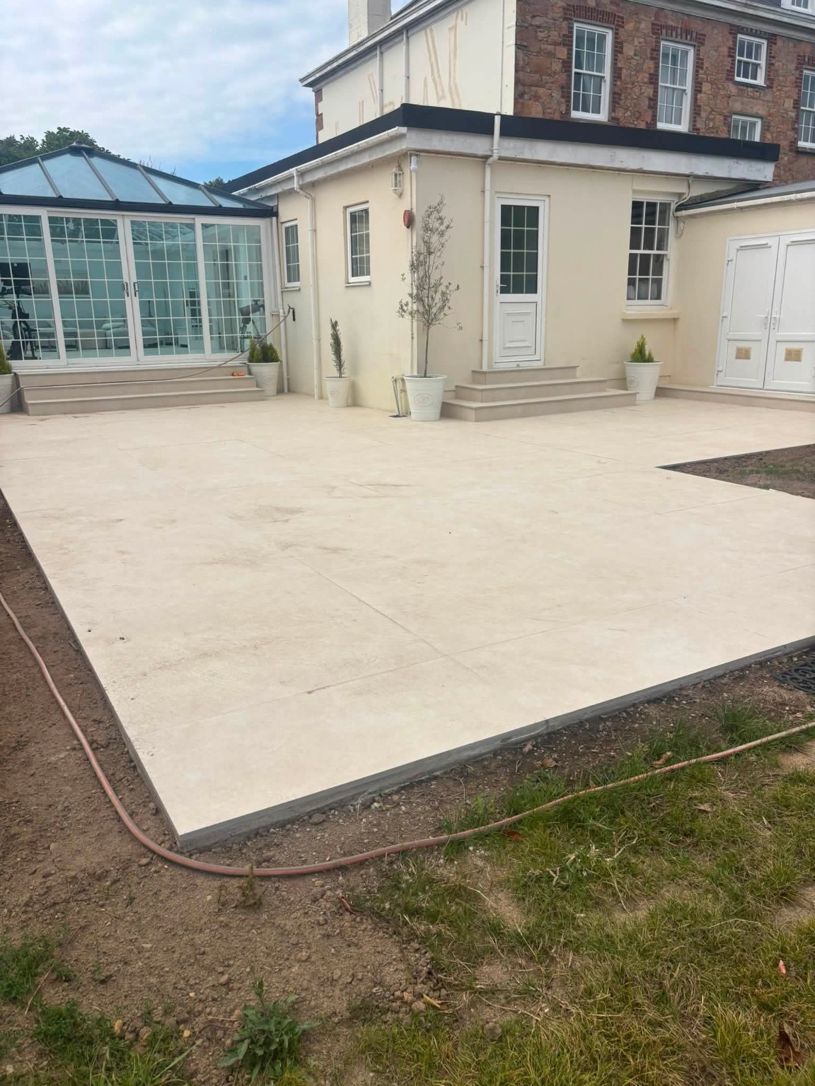 Completed stone terrace outside a conservatory and Jersey house